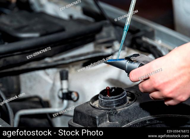 Kraftfahrzeugtechnik - Mechanikerin prüft Kühlflüssigkeit in einer Autowerkstatt bei einem Autoservice, Nahaufnahme