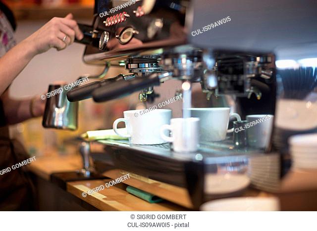 Cropped shot of waitress's using coffee machine in cafe