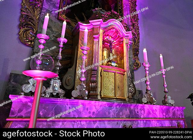 PRODUCTION - 09 May 2022, Baden-Wuerttemberg, Litzelstetten: The altar including the tabernacle of the churches of Saint Peter and Paul is illuminated in pink...