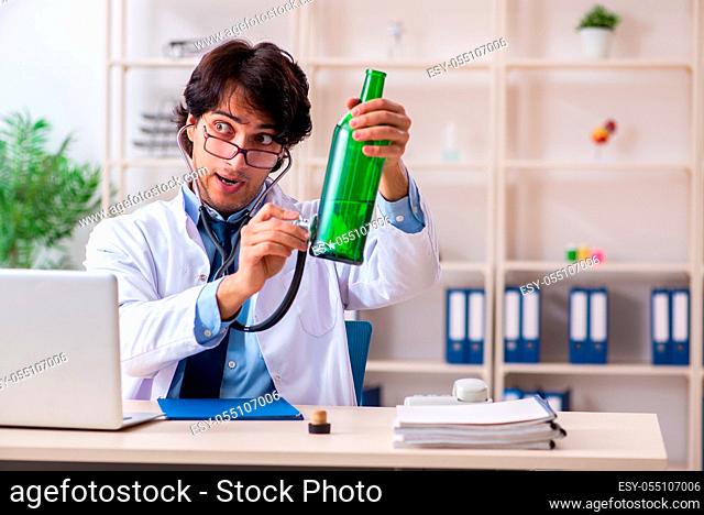 Young male doctor drinking in the office