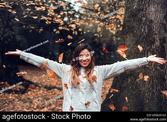 Portrait of a woman in the autumn park, throwing up fallen leaves. Toned image