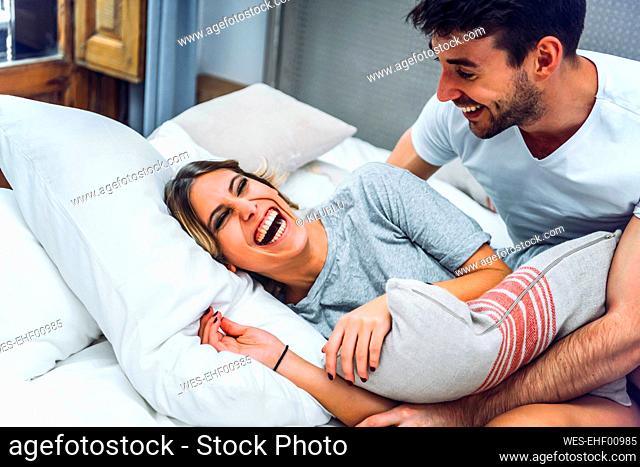 Laughing young couple lying in bed at home