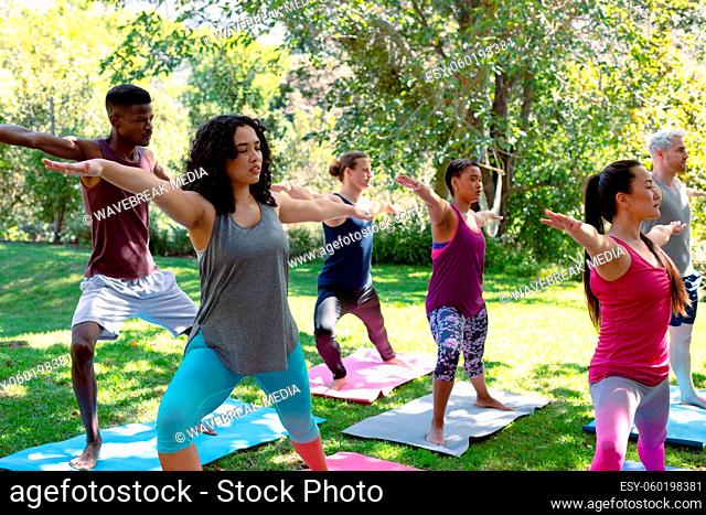 Group of diverse female and male people practicing yoga outdoors