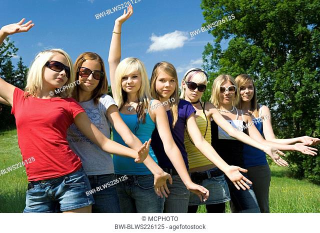 group of teenage girls posing in a meadow in a row behind each other