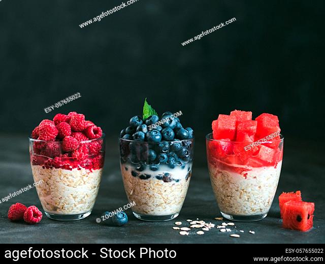 Healthy breakfast: overnight oats with fresh fruits and berries in glass. Overnight oatmeal porridge with watermelon, raspberry, blueberry, decorated mint