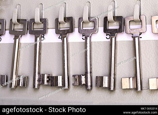 Row of old metal silver skeleton keys hanging in rack with numbers of the room. antique vintage keys organized