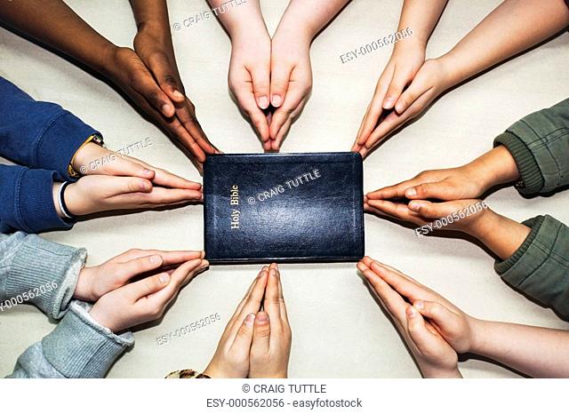 praying hands pointing to a bible