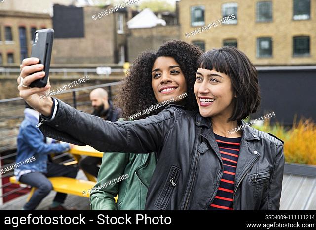 Portrait of Women on rooftop patio taking selfies with cell phone