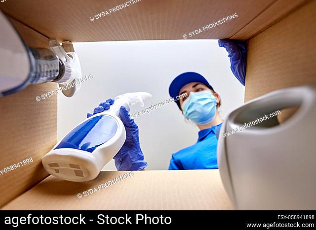 woman in mask packing cleaning supplies in box