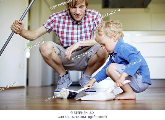 Boy helping father sweep floor