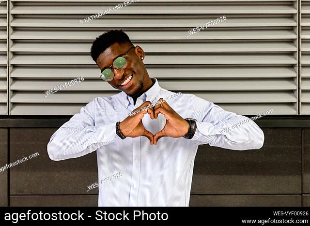 Smiling man making heart shape with hands