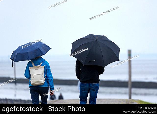 Harlesiel / Carolinensiel, Germany June 2020: Symbolic pictures - 2020 A woman and a man, with rain with umbrellas on the dike on the beach of Harlesiel