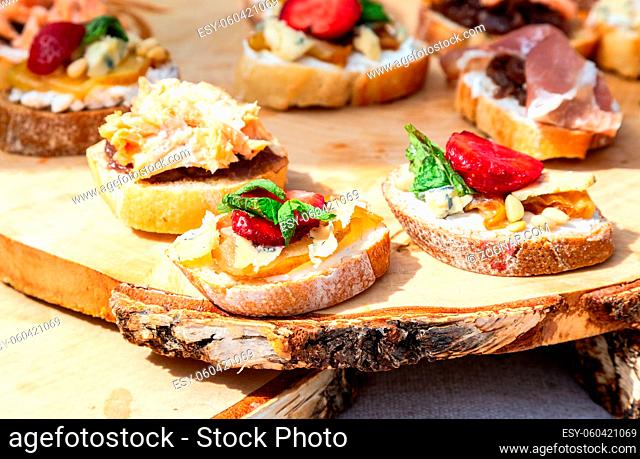 Tasty fresh sandwiches with different filling on wooden board