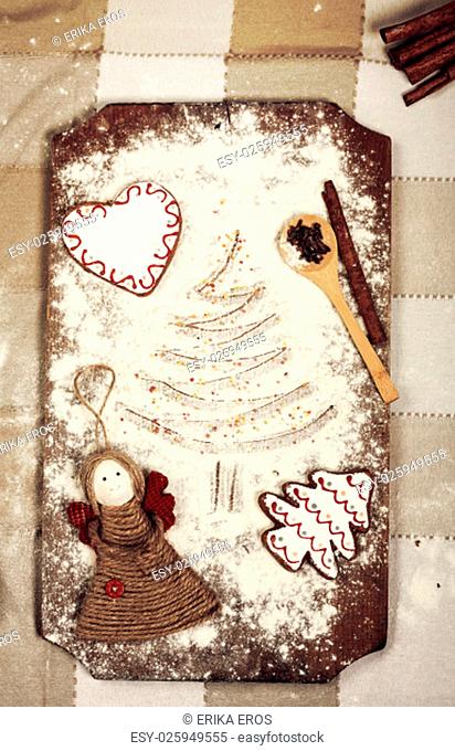 Christmas background with gingerbread cookies, spices and flour over wooden background