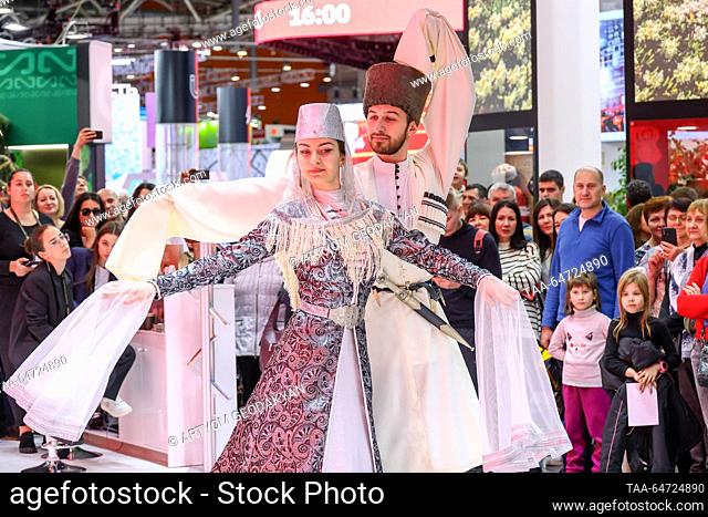 RUSSIA, MOSCOW - NOVEMBER 12, 2023: A woman and a man wearing traditional costume perform a folk dance at a stand of the North Ossetia-Alania Republic during...