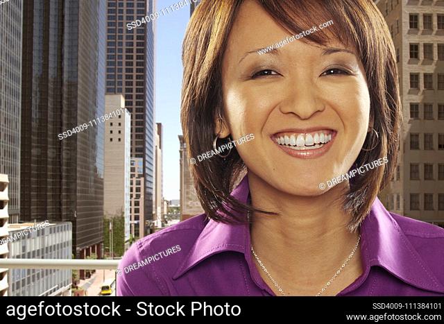 Smiling Asian businesswoman with city in background