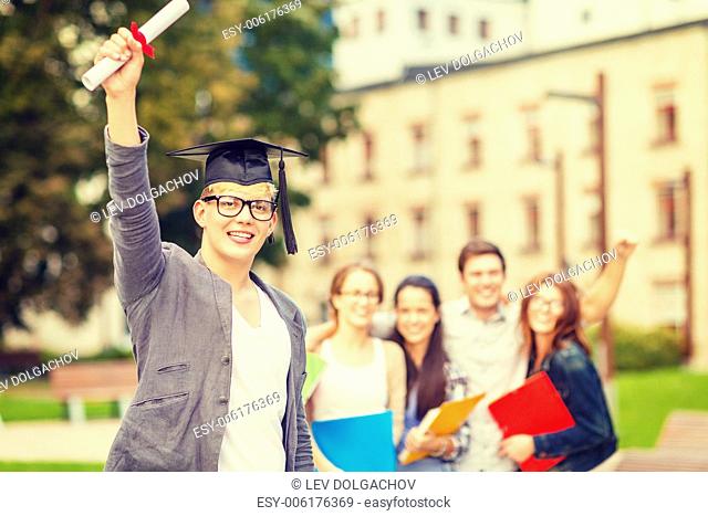 education, campus and teenage concept - smiling teenage boy in corner-cap and eyeglasses with diploma and classmates on the back