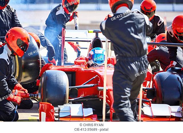 Pit crew working on formula one race car in pit lane
