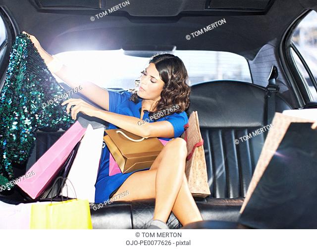 Woman with shopping bags in backseat of limo