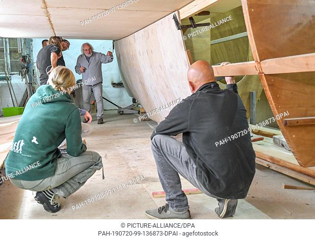 16 July 2019, Brandenburg, Kienitz-Nord: Frank Ladewig (M), President of the organization FYD-Adventure and several helpers are working in a hall on the shell...