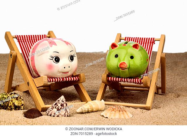 Liegestuhl mit Sparschwein am Sandstrand. Symbolfoto für Kosten bei Reise, Urlaub, Ferien. Sparen im Urlaub