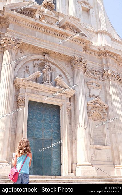 Girl in front of ornate stone building, Lecce, Puglia, Italy