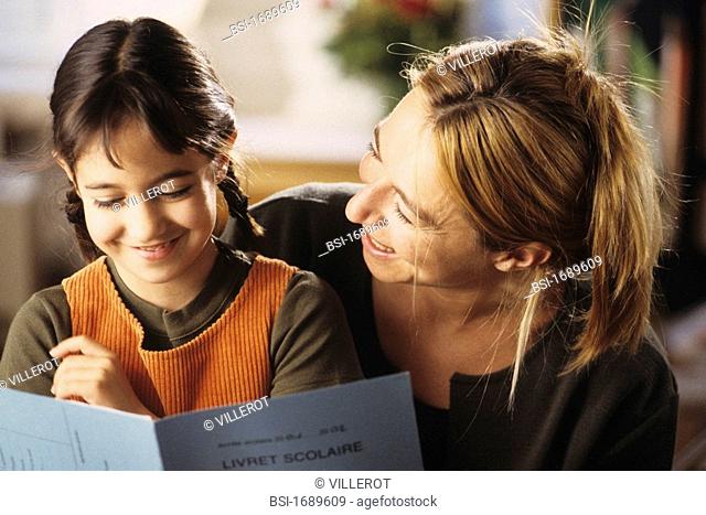 9-year-old girl showing her quarterly school report to her mother