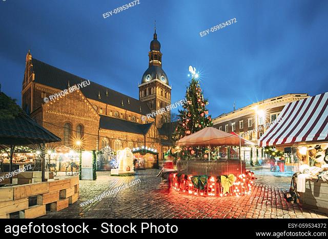 Riga, Latvia. Christmas Market On Dome Square With Riga Dome Cathedral. Christmas Tree And Trading Houses. Famous Landmark At Winter Evening Night In...