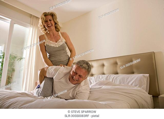 Mature couple wrestling on bed