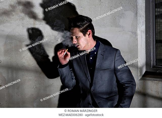 Germany, Bavaria, Young man smoking in dark corner