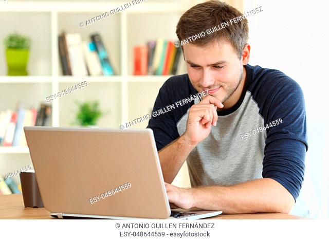 Man finding interesting content on line in a laptop on a table at home