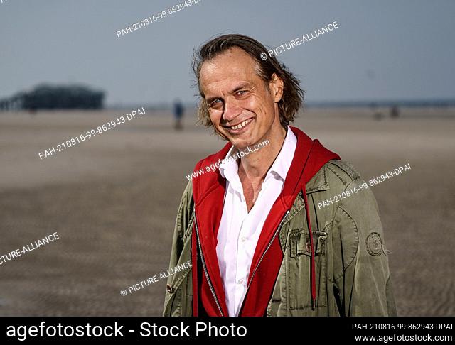 12 August 2021, Schleswig-Holstein, Sankt Peter-Ording: Actor Ralf Bauer stands on the beach of Sankt Peter-Ording in front of the waterline