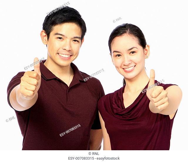 A couple in casual clothes doing the thumbs up hand sign
