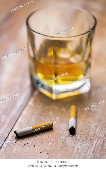 cigarette butts and glass of alcohol on table