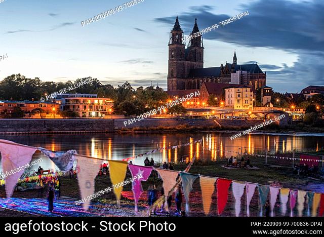 09 September 2022, Saxony-Anhalt, Magdeburg: On the Elbe meadows, young people dance in front of a historic backdrop, Magdeburg Cathedral