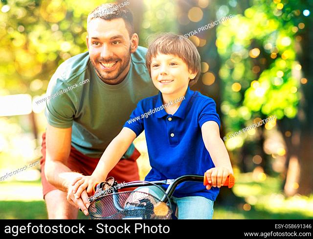 father teaching little son to ride bicycle at park