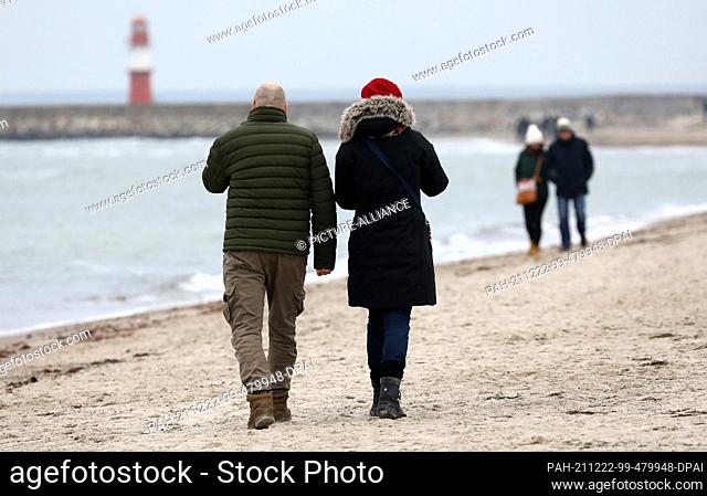 22 December 2021, Mecklenburg-Western Pomerania, Warnemünde: Only a few walkers are out and about on the Baltic Sea beach in the grey North German grimy weather