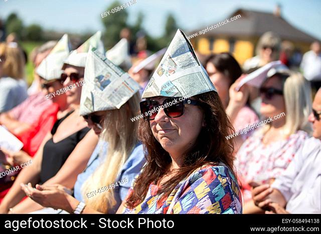 August 29, 2020. Belarus, village Lyaskovichi. City holiday. Women spectators in the heat put on hats from the newspaper