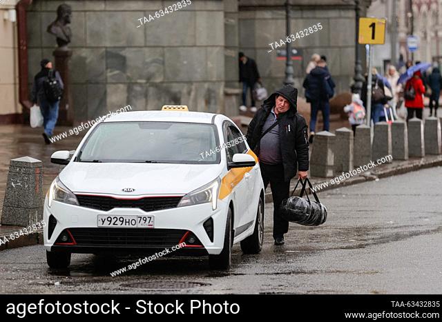 RUSSIA, MOSCOW - OCTOBER 16, 2023: A man with luggage looks at a taxi car in Komsomolskaya Square during rain. Mikhail Sinitsyn/TASS