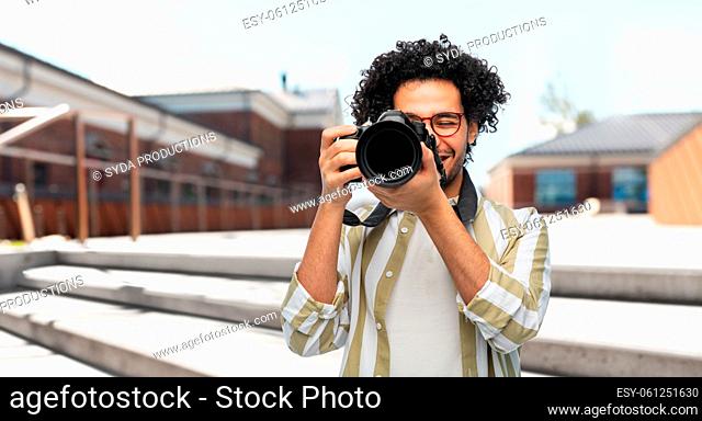 smiling man or photographer with digital camera