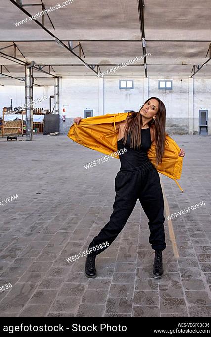 Modern female dancer in yellow jacket at abandoned factory