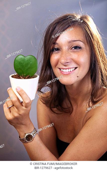 Caucasian woman holding flower pot with succulent plant in the shape of a heart