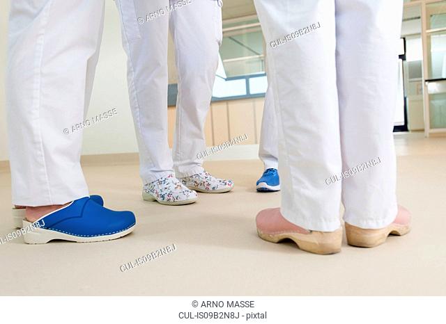 Low section of group of nurses wearing surgical scrubs and clogs