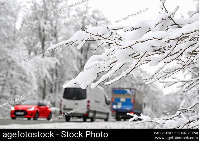 04 December 2023, Baden-Württemberg, Bebenhausen: Cars drive through a snow-covered forest. Photo: Bernd Weißbrod/dpa. - Bebenhausen/Baden-Württemberg/Germany