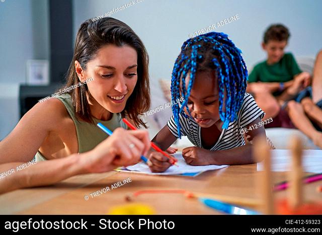 Mother and toddler daughter coloring at home