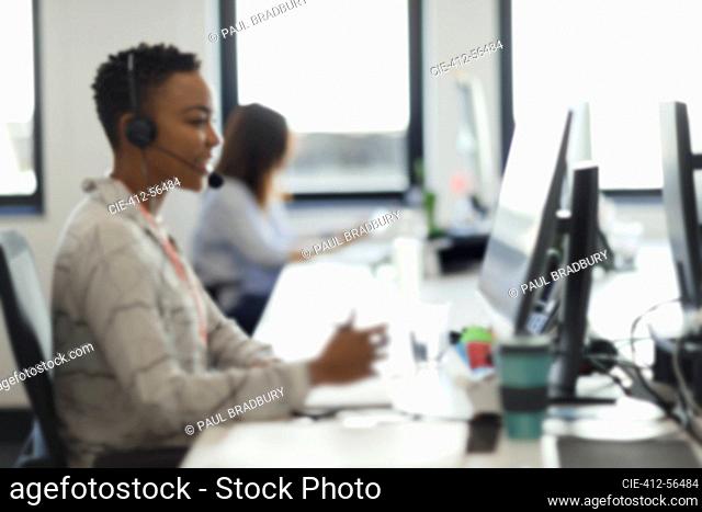 Businesswoman in headset working at computer in call center office