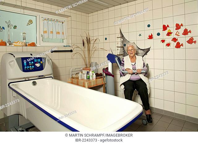 Elderly woman sitting in a bath lift, medical aid