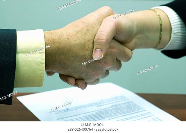Shaking hands above a signed contract