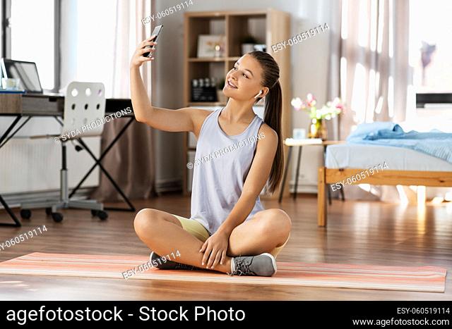 girl with phone and earphones takes selfie at home