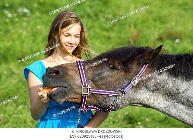 young girl giving a carrot to her horse